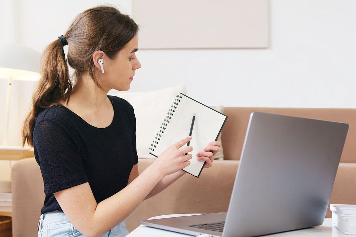 A woman taking notes during an online class